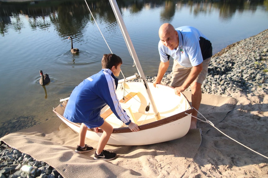 Ian Manson and his grandson Nah push their boat into the water, a happy multigenerational family arrangement.