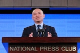 Wang Xining stands at the National Press Club podium.