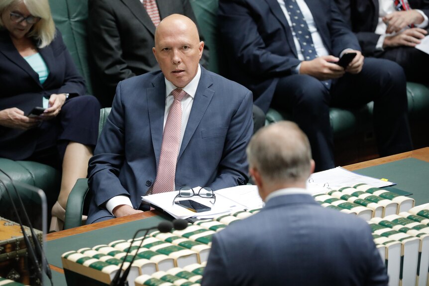 Peter Dutton looks across the desk to where Anthony Albanese is standing. 