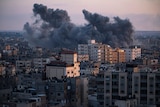 Thick black and grey smoke rises above multistorey buildings following an airstrike.