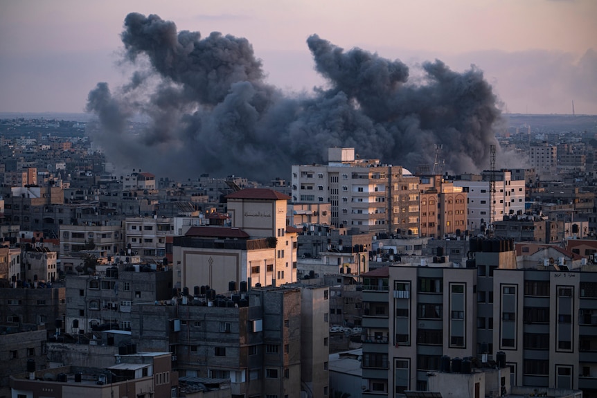 Thick black and grey smoke rises above multistorey buildings following an airstrike.