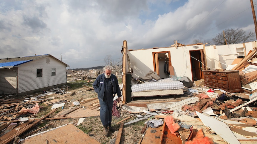 A man in what remains of his tornado-ravaged home