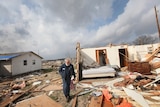 A man in what remains of his tornado-ravaged home