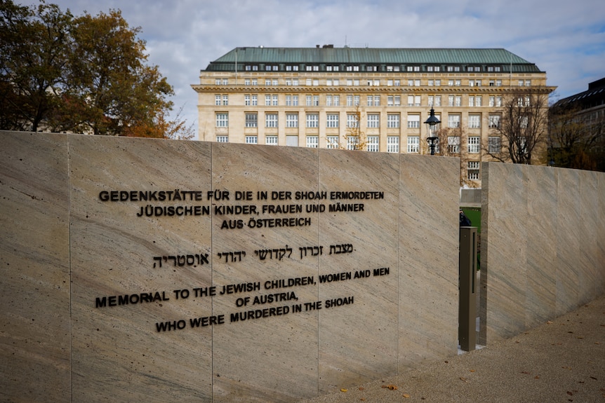 The entrance wall to a war memorial is shown bearing writing in different languages