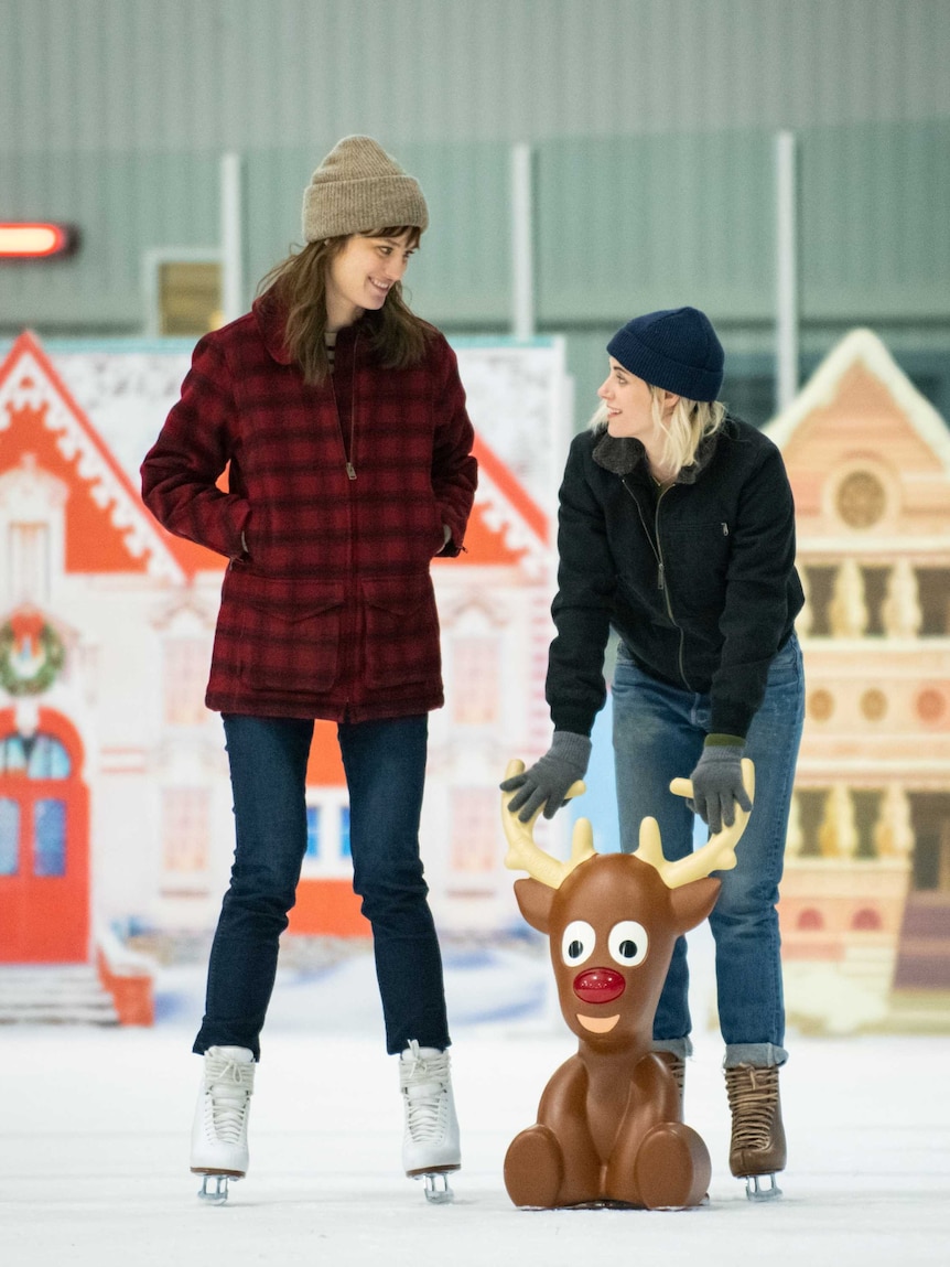 Actors Mackenzie Davis and Kristen Stewart ice skating together in the movie Happiest Season