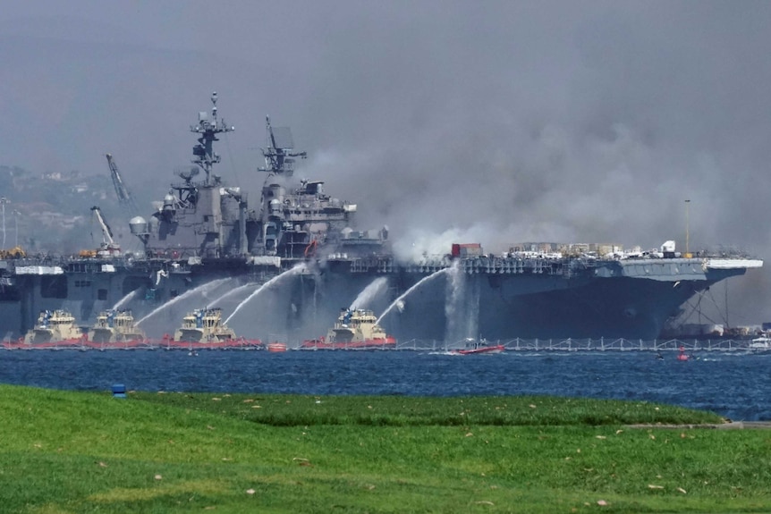 Firefighting boats spray water onto the U.S. Navy amphibious assault ship USS Bonhomme Richard