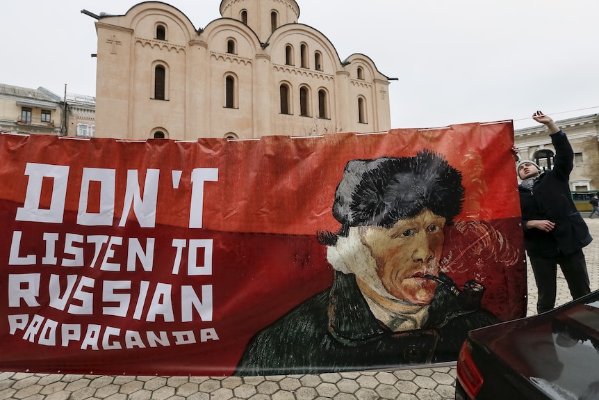 Un activist ține un banner cu o fotografie a artistului olandez Vincent van Gogh la demonstrații în fața ambasadei olandeze din Kiev.