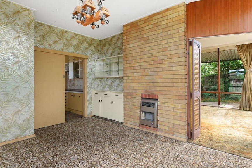 A tiled dining room with heater, exposed bricks and floral wallpaper.
