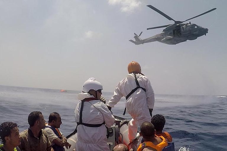 A helicopter hovers over the area where a vessel carrying up to 700 migrants capsized off the coast of Libya.