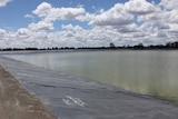 A large water holding pond at the Narrabri Gas Project, framed by thick black plastic.