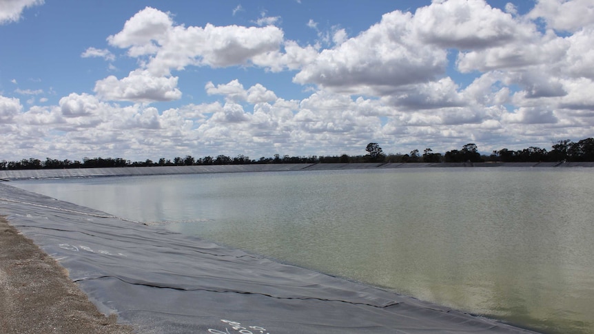 A large water holding pond at the Narrabri Gas Project, framed by thick black plastic.
