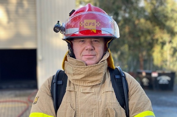 A male firefighter wearing a red hat and a yellow coat