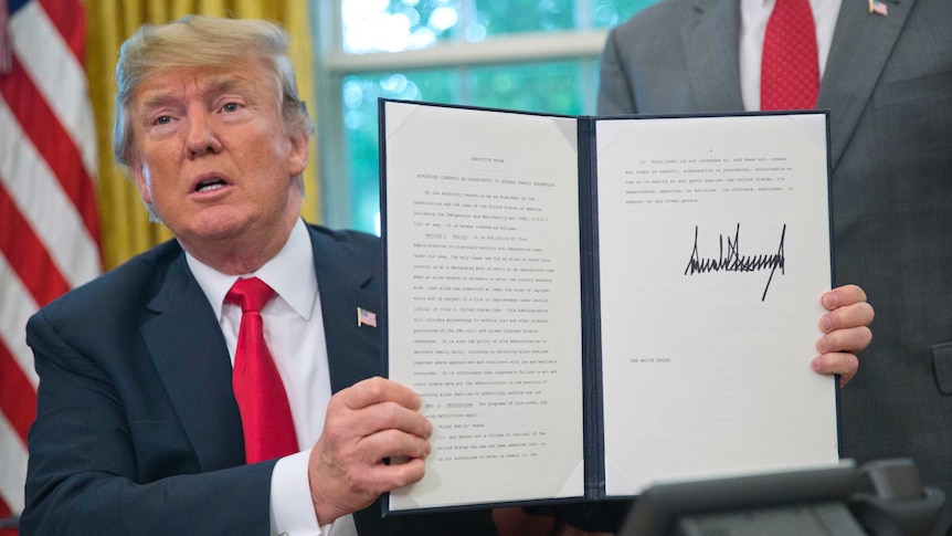 Donald Trump holds up the executive order he had just signed.