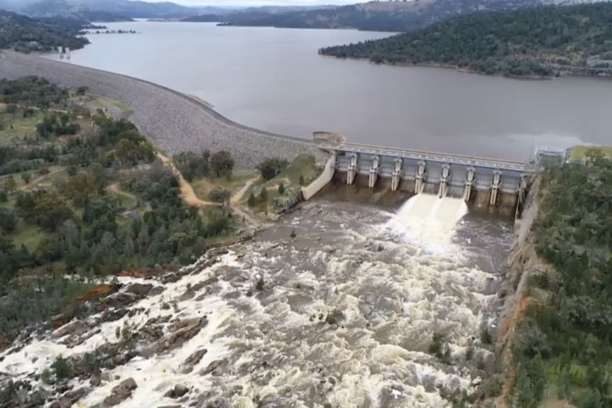 Aerial shot of dam with water pouring out of gates