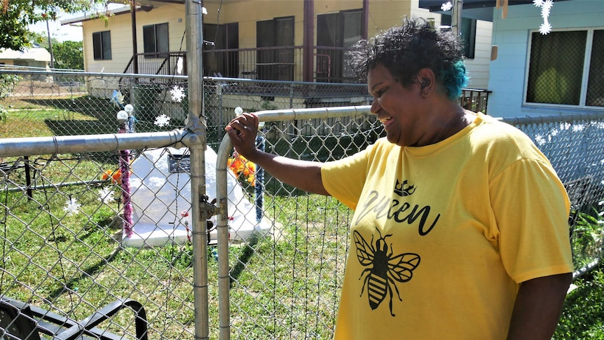 Indigenous woman smiles as she closes the gate to protect the decorated memorial rock