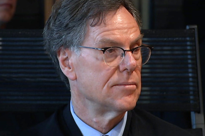A headshot of a judge wearing glasses and a black judicial robe.