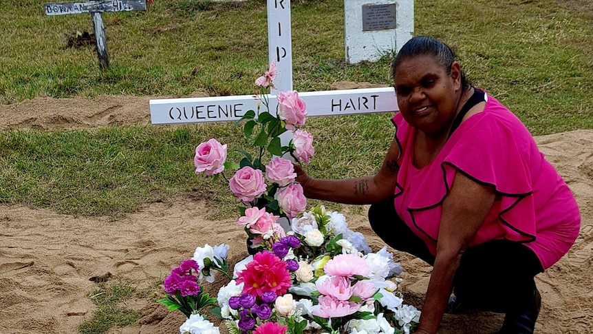 Debbie West knees by her auntie's grave, which is covered in flowers