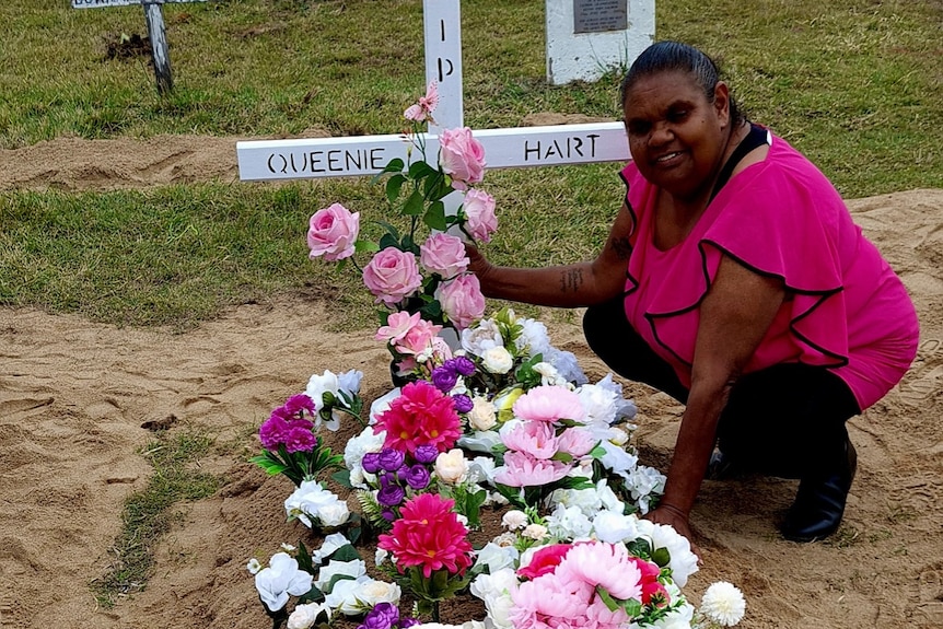 Debbie West knees by her auntie's grave, which is covered in flowers