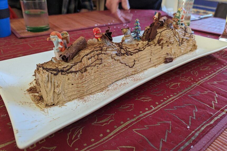 A delicious Yule log cake, covered in adornments and light brown icing