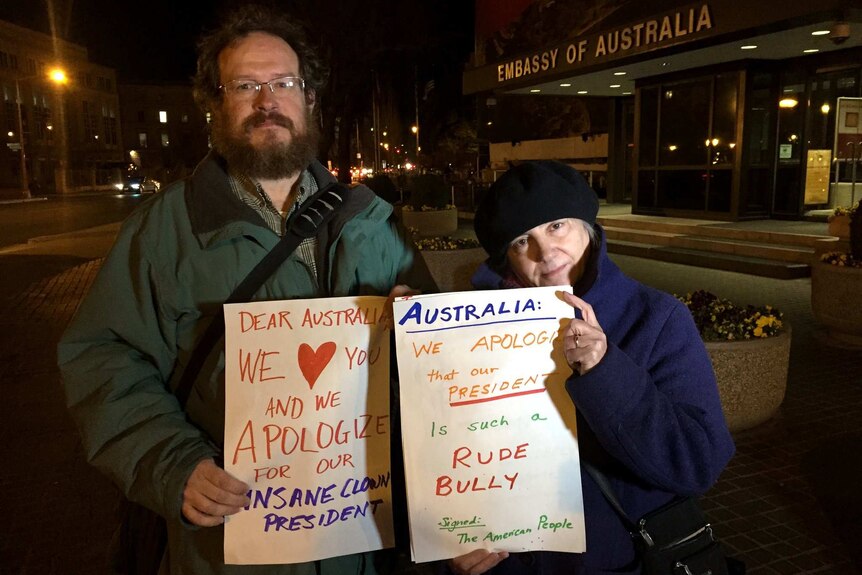 Americans stand outside the Australian Embassy in Washington, holding signs apologising for Donald Trump.