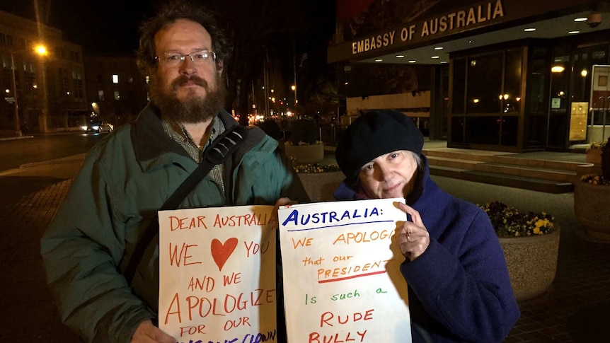 Trump Protestors hold signs apologising to Australia