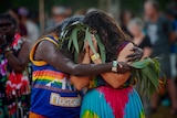 Two dancer embrace holding eucalyptus leaves 