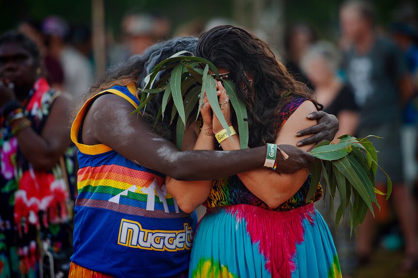 Two dancer embrace holding eucalyptus leaves 