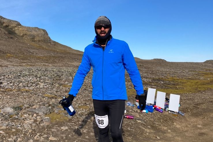 A man wearing warm clothing stands in Antarctica.