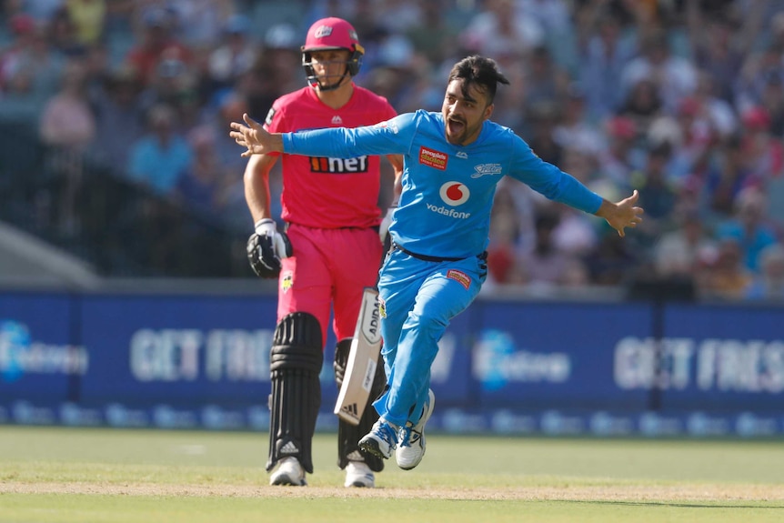 A bowler runs with his arms out like an airplane to celebrate his third wicket in as many balls.