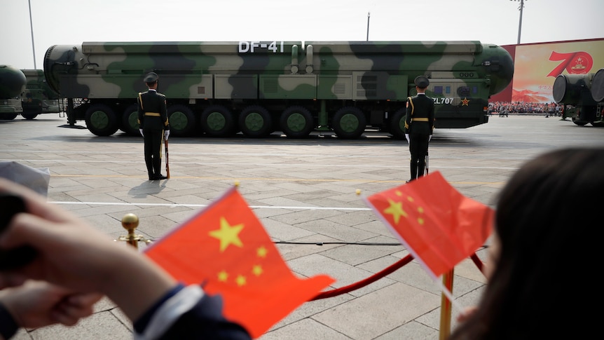  Spectators wave Chinese flags as military vehicles carrying DF-41 ballistic missiles roll during a parade.
