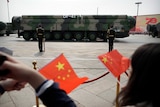  Spectators wave Chinese flags as military vehicles carrying DF-41 ballistic missiles roll during a parade.