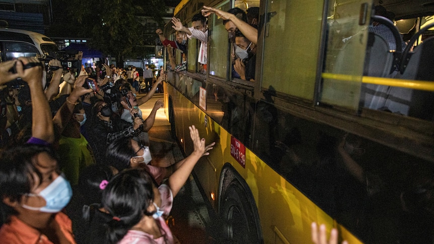 People wave to passengers on a bus.