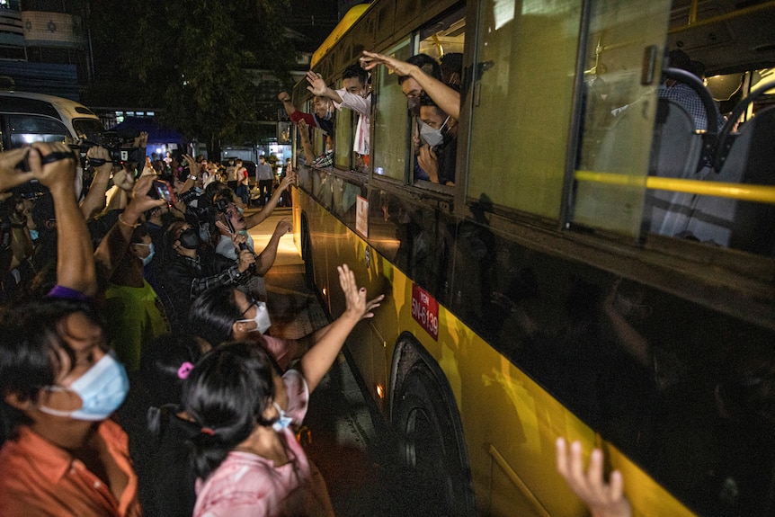 People wave to passengers on a bus.