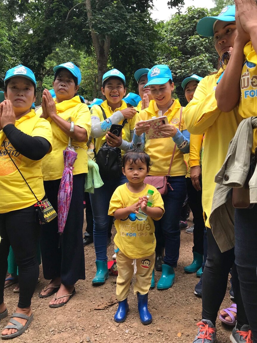 Volunteers in yellow tshirts and blue caps praying.