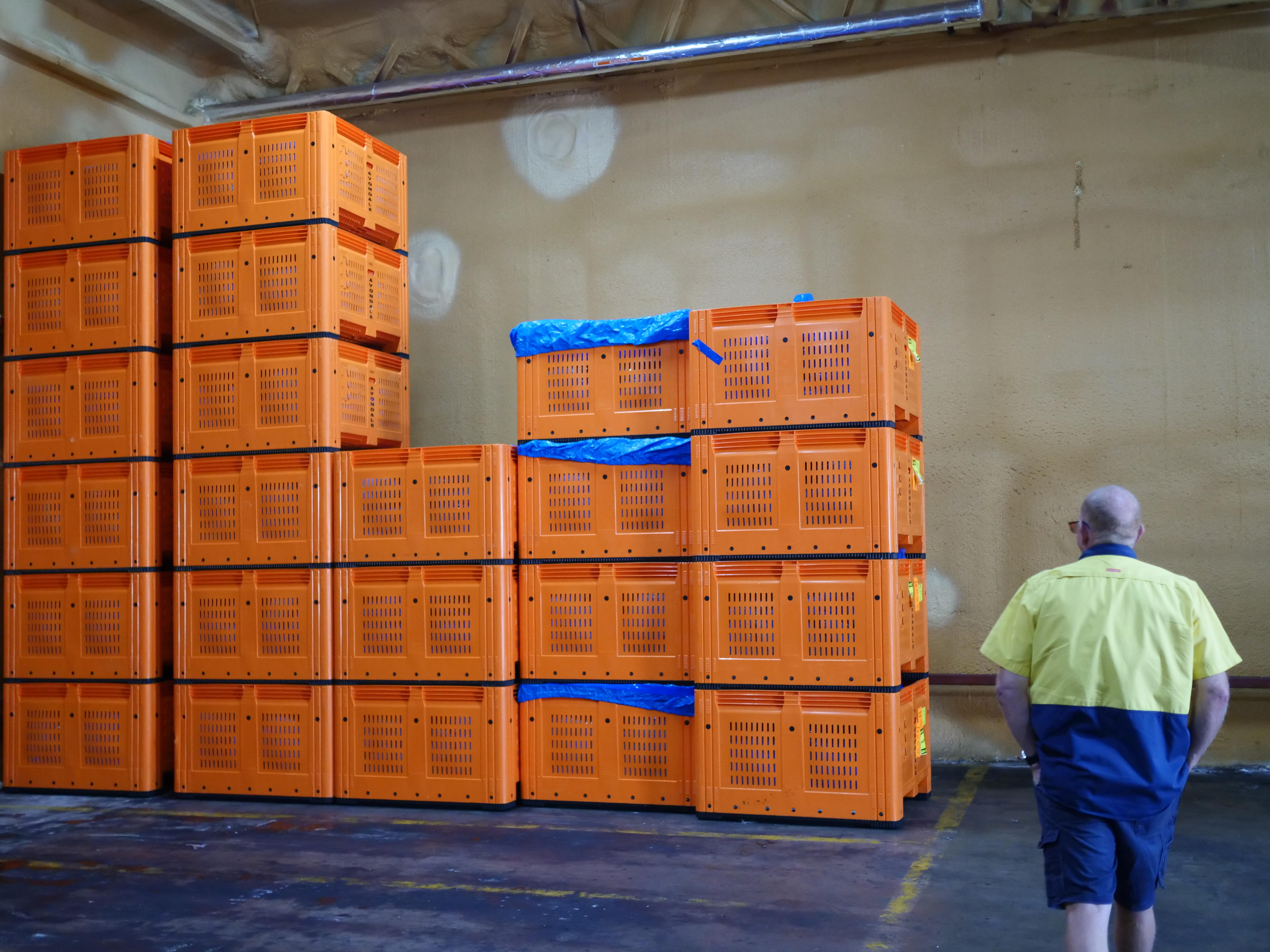 El hombre camina hacia una pila de cajas de color naranja brillante contra una pared