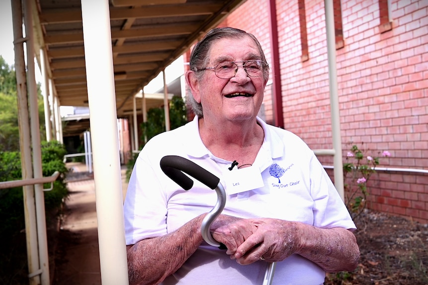 A man with a cane in an outdoor hallway