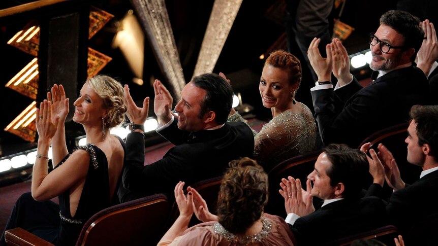 Cast and crew from silent film The Artist applaud as French composer Ludovic Bource wins the Oscar for the Best Original Score