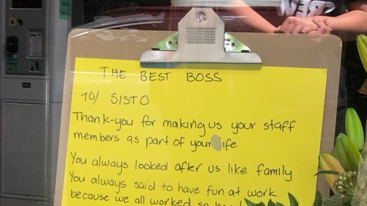 A clipboard in a window with writing on a yellow piece of paper.