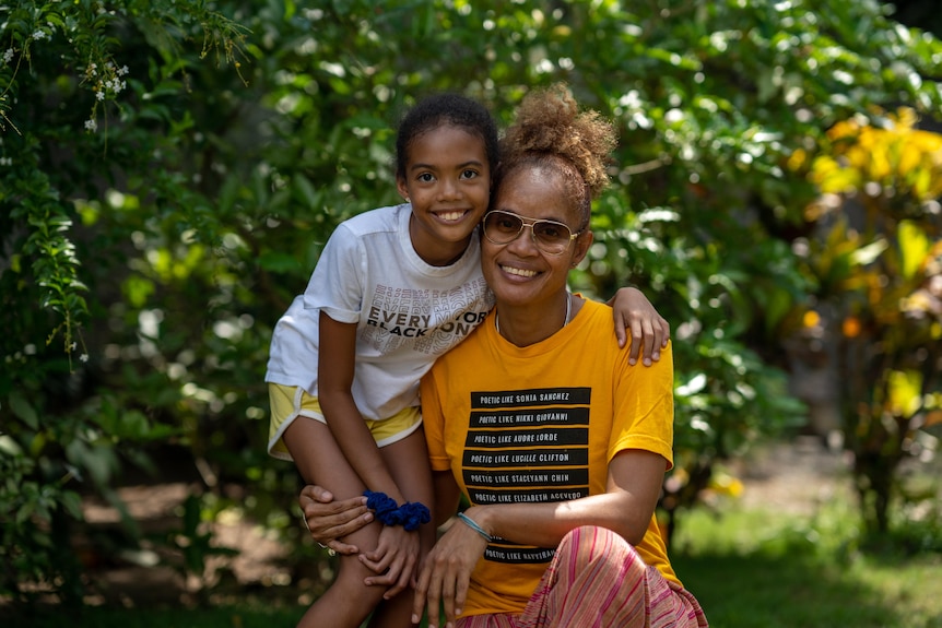 A Jamaican woman and a girl hold signs reading "princesses belong in fairy tales, not Jamaica"