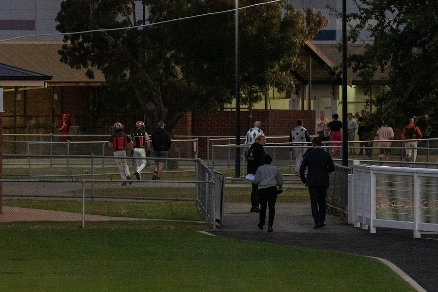 People leave a building and walk back to the stables.