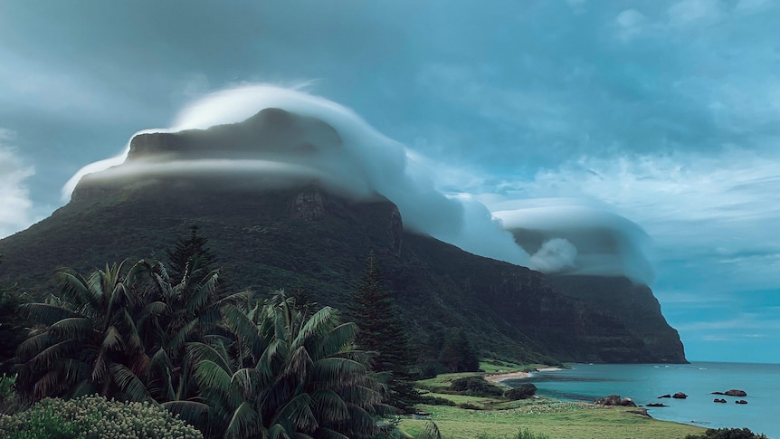 Clouds cover the peak of a mountain on an island.