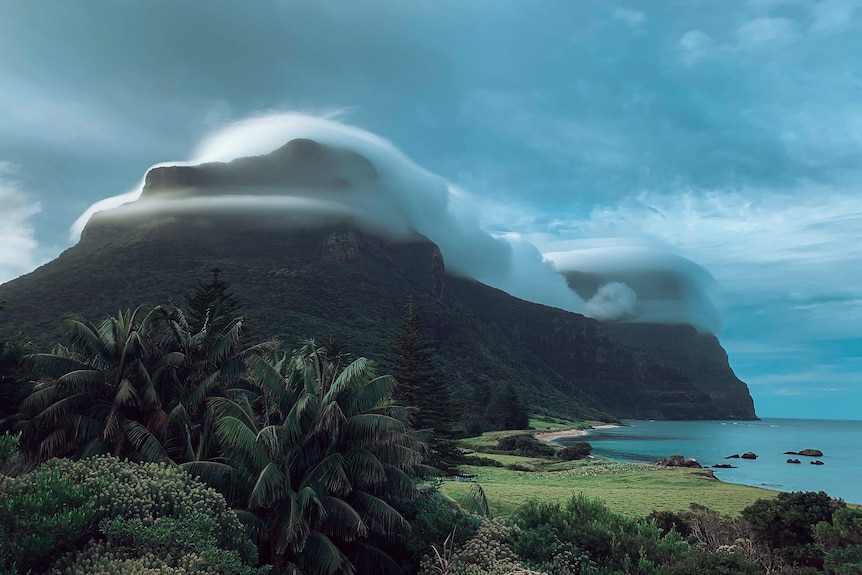 Clouds cover the peak of a mountain on an island.
