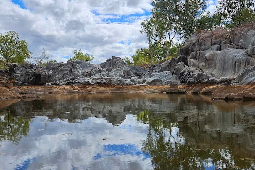 an outback waterhole surrounded by rocks and trees