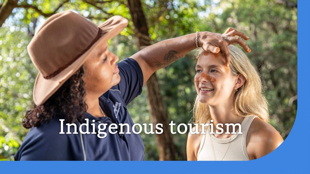 Indigenous tourism: An Indigenous woman paints brown paint on a blonde woman's head.