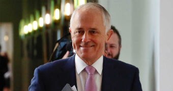 Prime Minister Malcolm Turnbull smiles as he walks through the halls of Parliament House holding his ipad