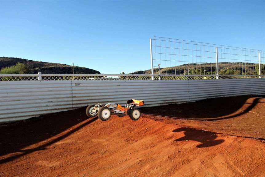 A remote control car clears a speed bump on the race track.