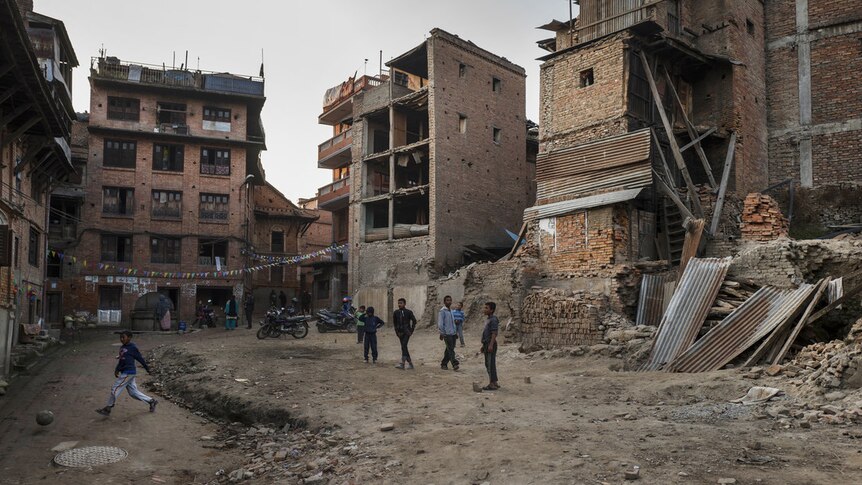Nepal children play amongst destroyed buildings