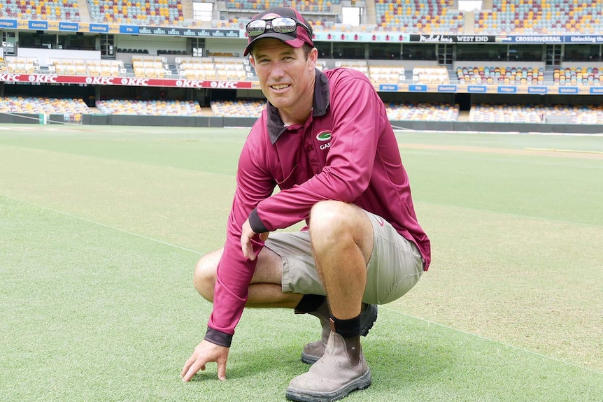 Brisbane cricket ground curator David Sandurski kneels on the grass of the Gabba