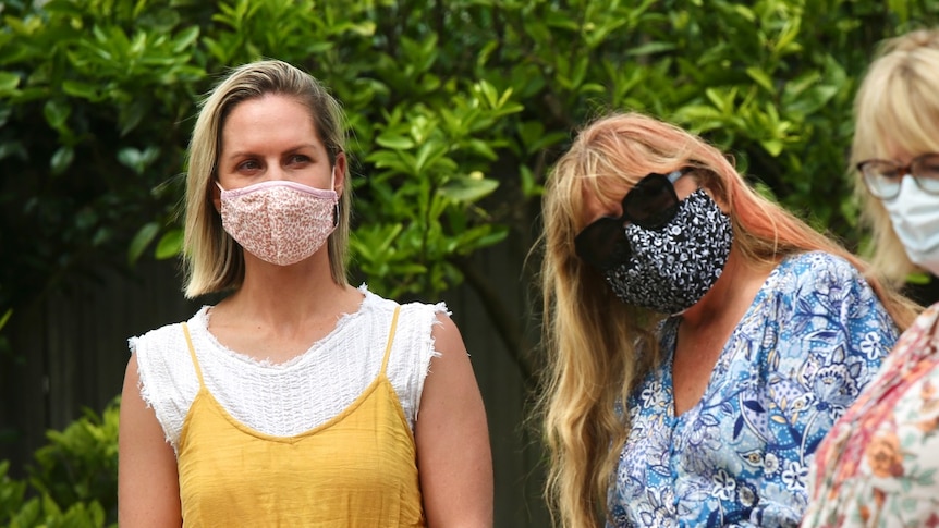 Two women wearing masks standing outside.