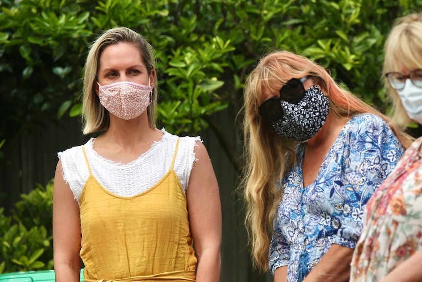 Two women wearing masks standing outside.